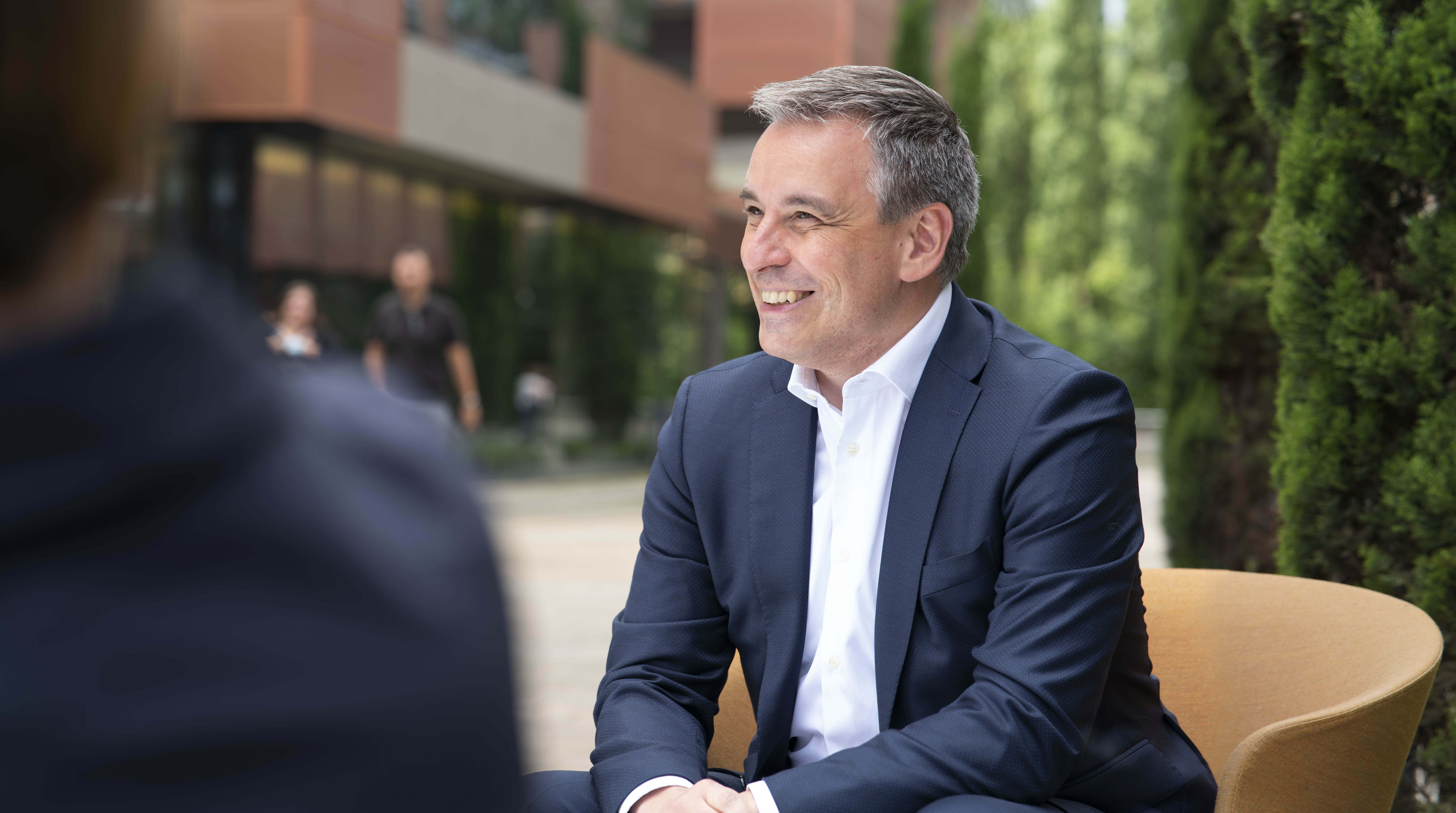 Le ministre CLaude Meisch est assis souriant dans la cour dw son ministère à Clausen  
